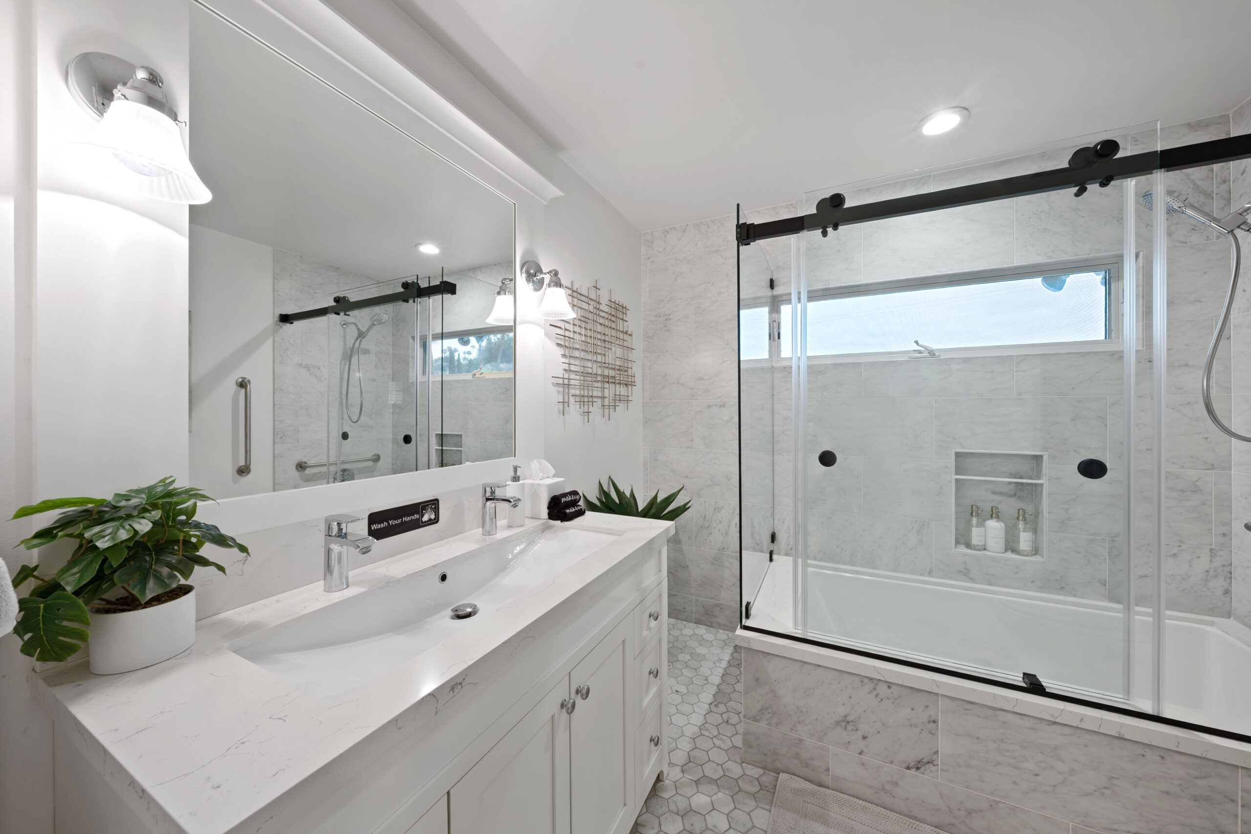 Modern bathroom with white marble countertop, double sinks, and a glass-enclosed shower.